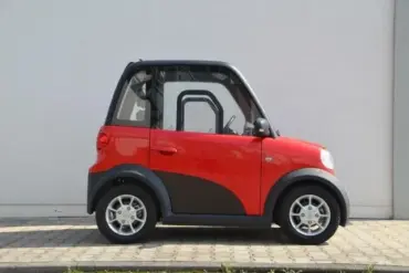Seitenansicht des roten ARI 802 Elektrofahrzeugs vor einer Mauer, das die kompakten Maße und das zweisitzige Konzept zeigt.