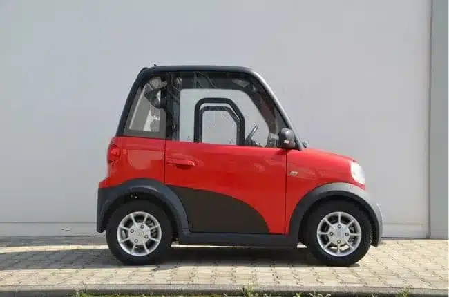 Seitenansicht des roten ARI 802 Elektrofahrzeugs vor einer Mauer, das die kompakten Maße und das zweisitzige Konzept zeigt.