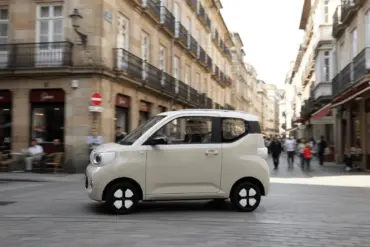 ARI Bruni Elektroauto fährt durch eine schmale Innenstadtstraße mit historischen Gebäuden.