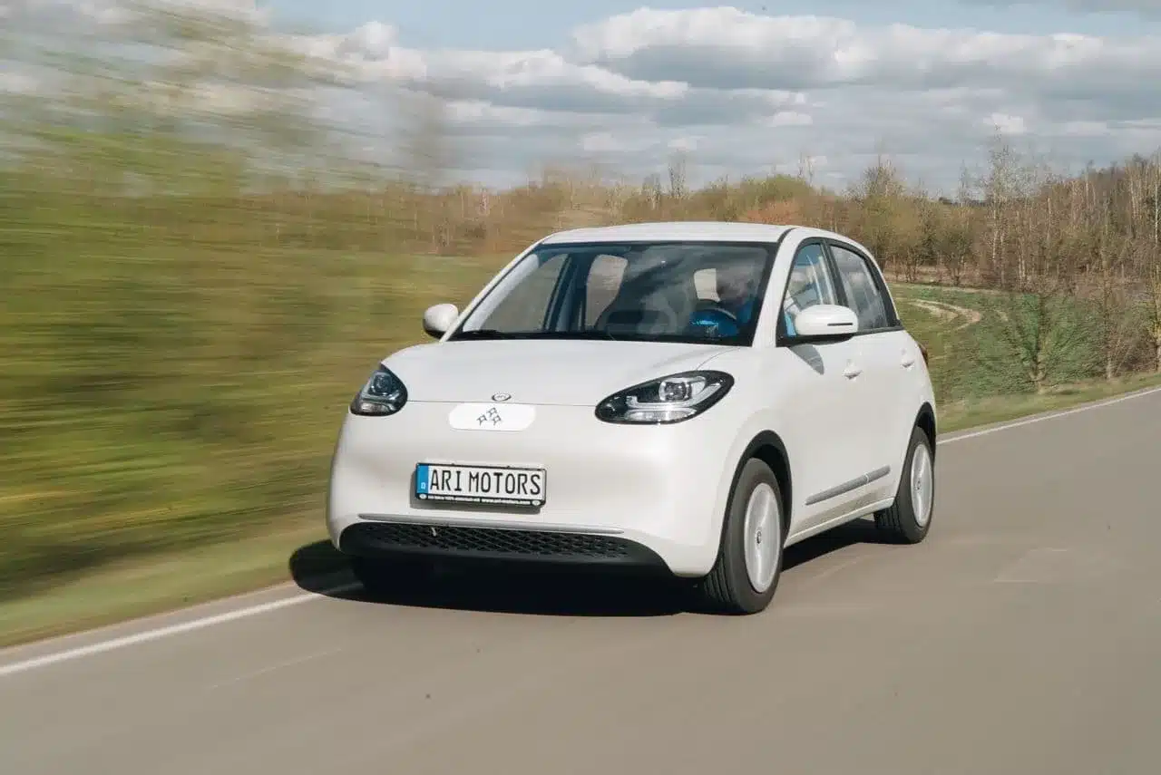 ARI Poly Elektroauto fährt auf einer Landstraße durch die Natur.
