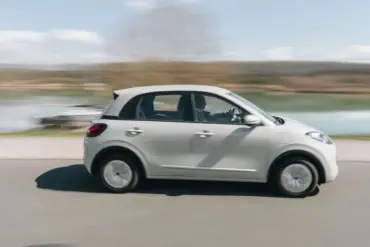 Seitenansicht des fahrenden ARI Poly Elektroautos in städtischer Umgebung