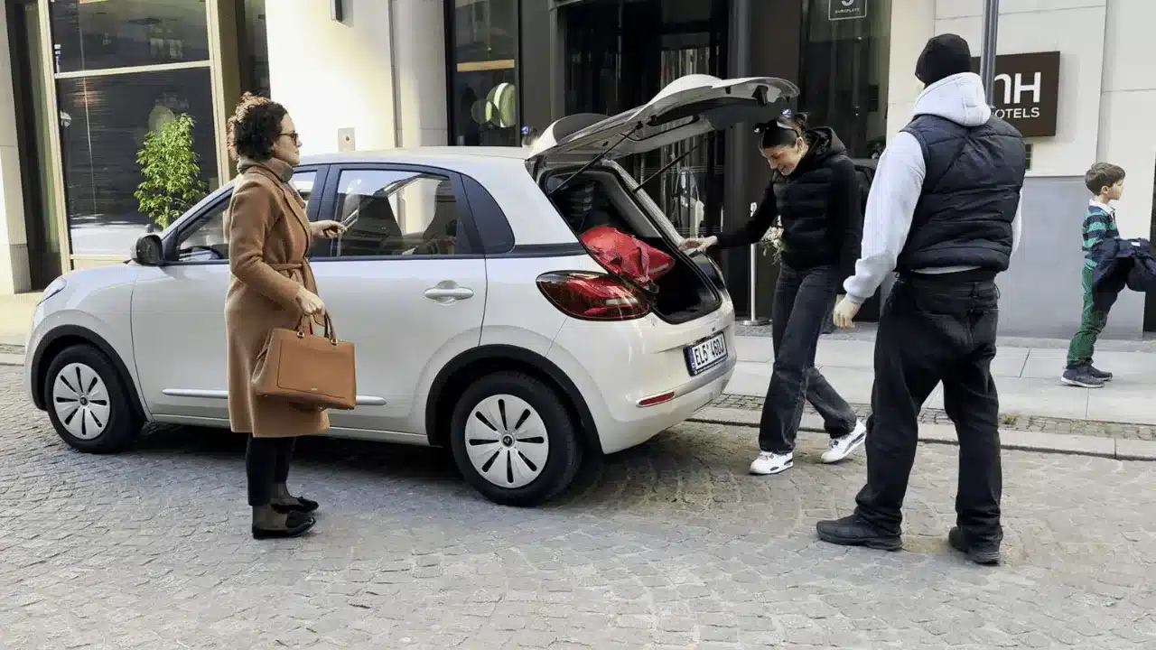 ARI Poly Elektroauto mit geöffnetem Kofferraum und Personen auf einer Stadtstraße