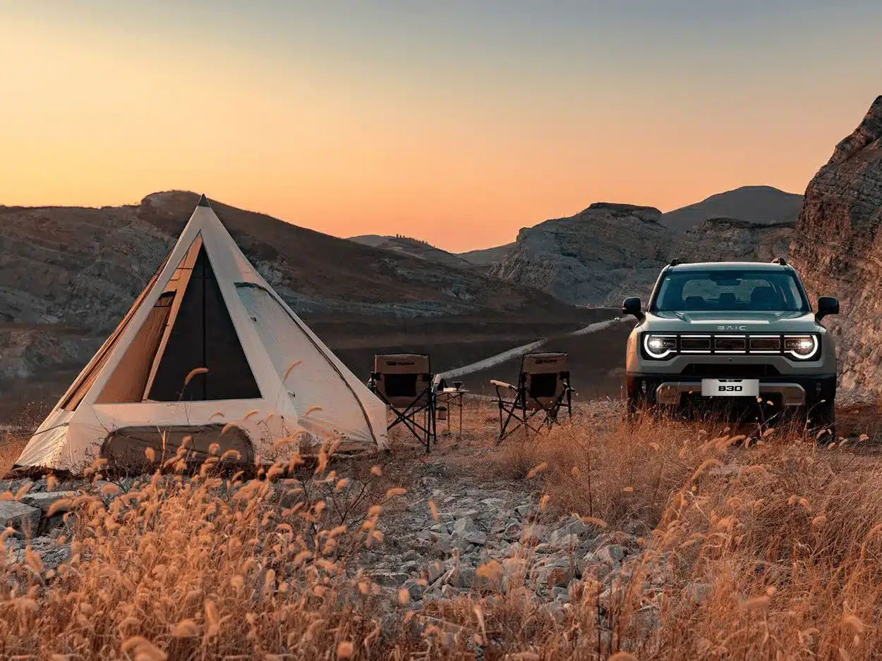 BAIC B30 SUV vor Zelt und Campingausrüstung in einer felsigen Landschaft bei Sonnenuntergang