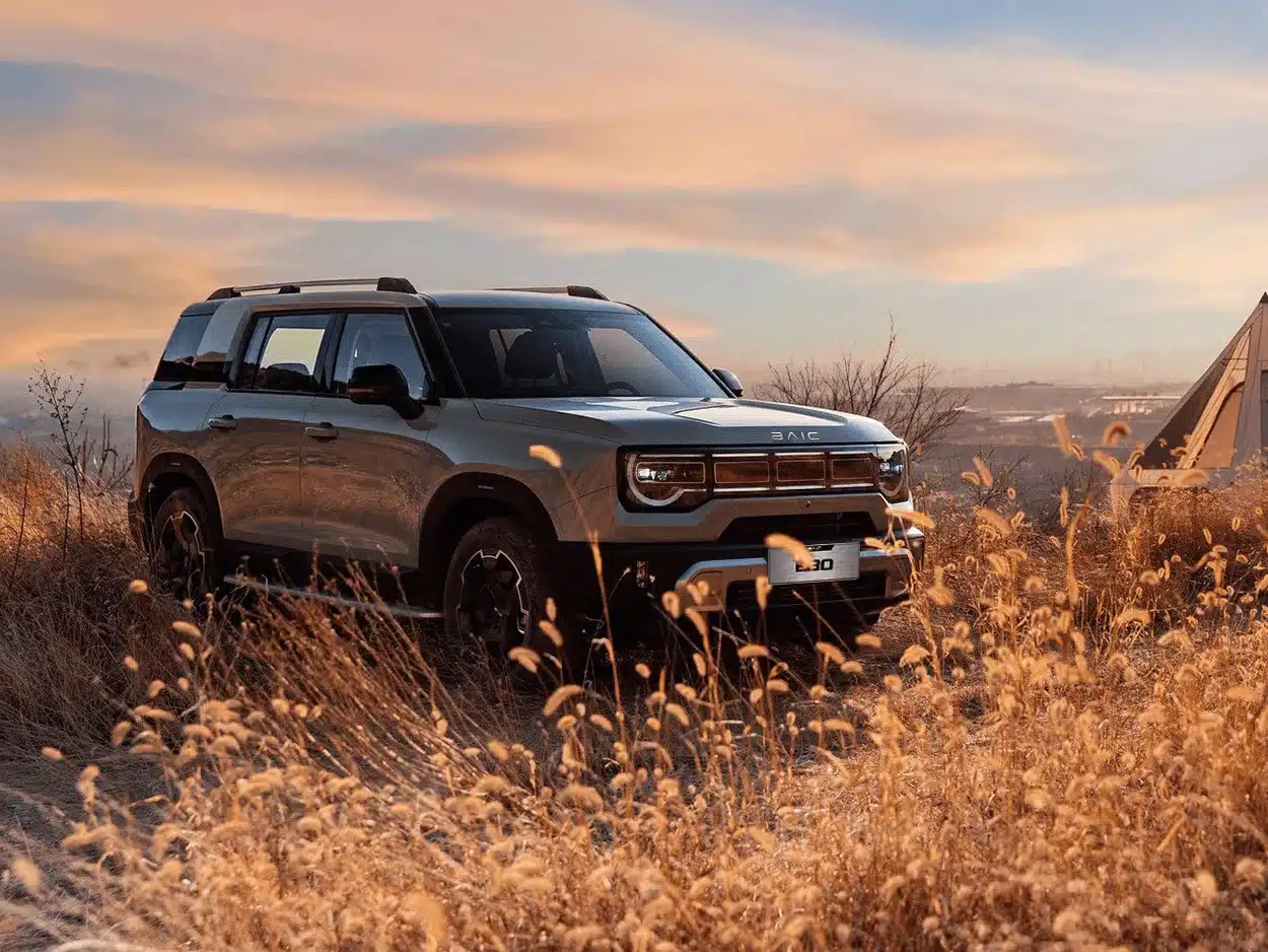 BAIC B30 SUV steht im trockenen Gras bei Sonnenuntergang, robustes Design und markante Front sichtbar.