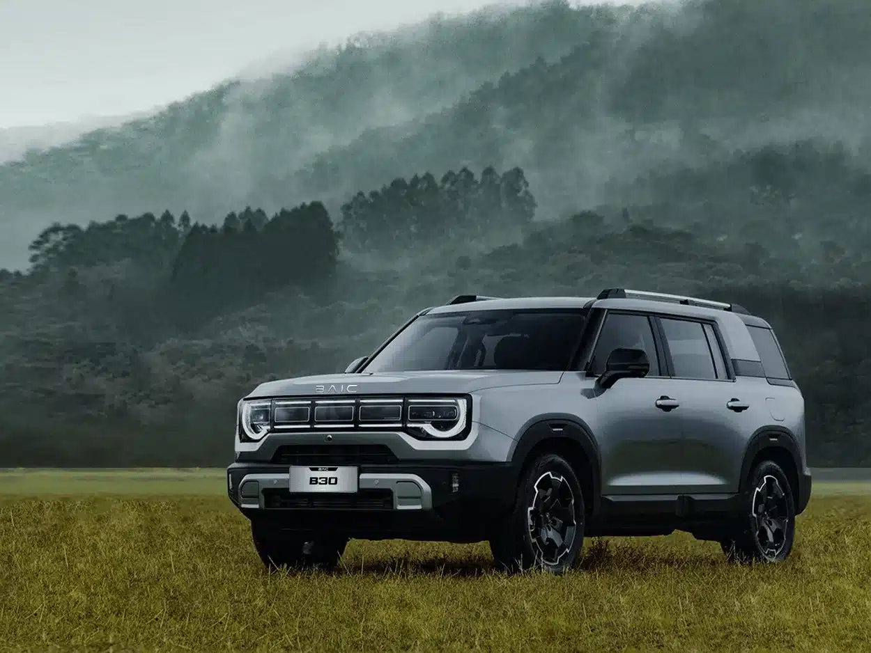 Der BAIC B30 SUV steht auf einer Wiese vor nebligen Bergen und zeigt seine markante Front mit fünfteiligem Tagfahrlichtband.