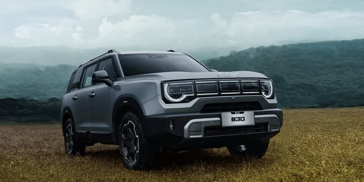 BAIC B30 SUV mit markantem Design und auffälligem Tagfahrlicht, stehend auf einem Feld vor bewaldeter Hügelkulisse.