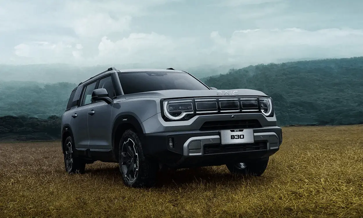 BAIC B30 SUV mit markantem Design und auffälligem Tagfahrlicht, stehend auf einem Feld vor bewaldeter Hügelkulisse.