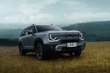 BAIC B30 SUV mit markantem Design und auffälligem Tagfahrlicht, stehend auf einem Feld vor bewaldeter Hügelkulisse.