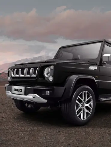 Schwarzer BAIC BJ80 SUV steht auf offener Landschaft mit Bergen und bewölktem Himmel im Hintergrund.