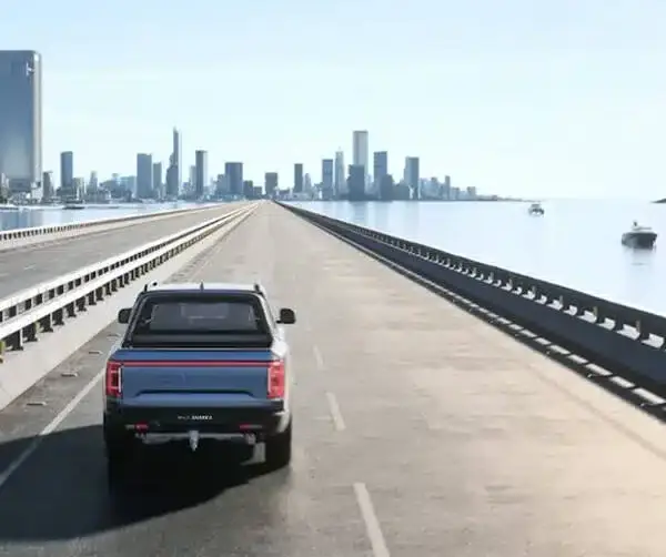 Der BYD Shark 6 Pickup fährt über eine Brücke in Richtung einer modernen Skyline