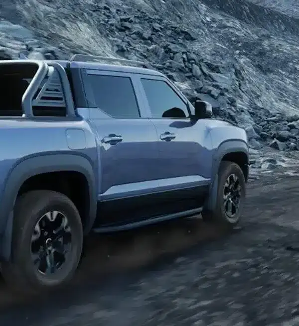 BYD Shark 6 Pickup in blau fährt über eine felsige Bergstraße.