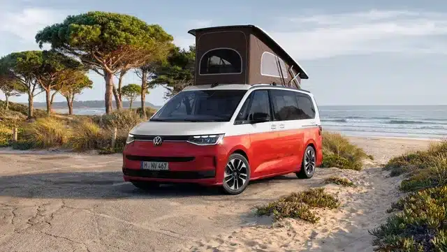 VW California Ocean Generation, rot-weiß, mit geöffnetem Aufstelldach am Strand