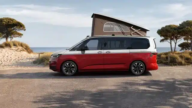Seitenansicht eines Volkswagen California Ocean „Generation“ mit offenem Aufstelldach und Bi-Color-Lackierung am Strand.