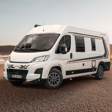 WEINSBERG CaraBus EDITION [FIRE] Camper Van steht auf sandigem Untergrund vor einer Meereskulisse.