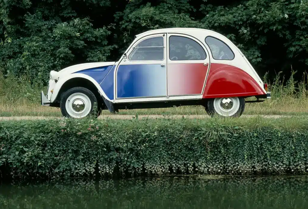 Citroën 2CV Cocorico Sondermodell von 1986, Seitenansicht mit Trikolore-Lackierung vor grüner Natur.