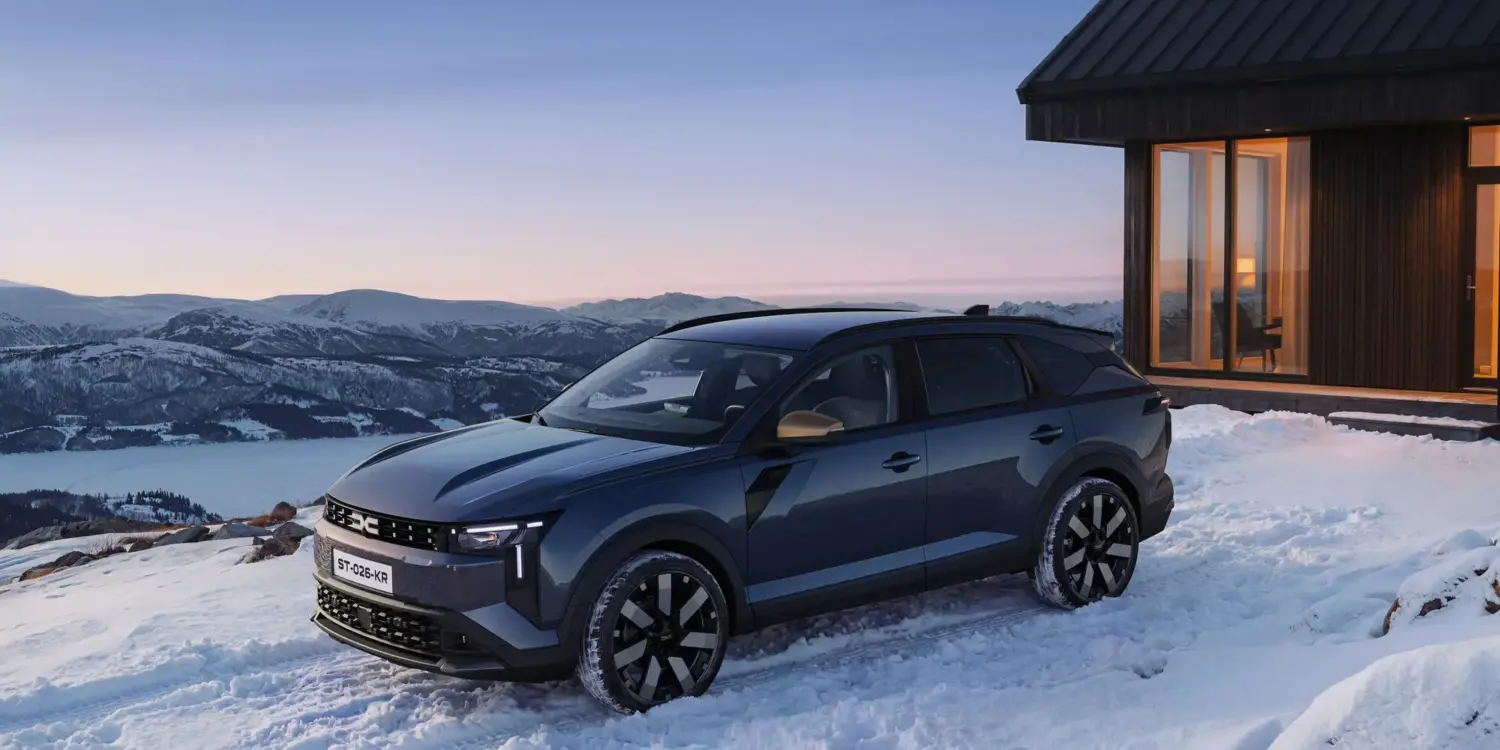 Dacia Striker bei Sonnenuntergang in verschneiter Berglandschaft vor moderner Hütte