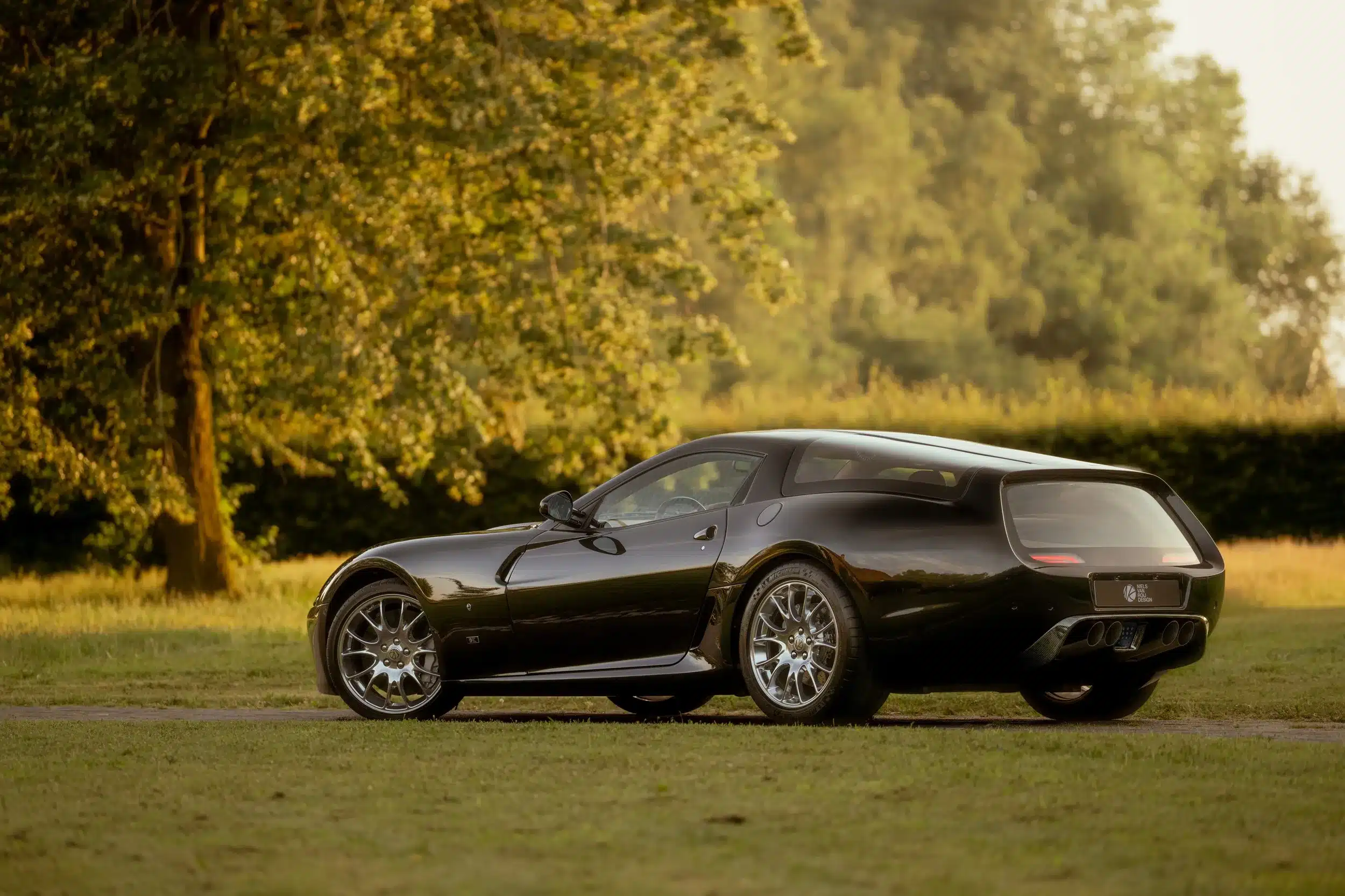 Der Daytona Shooting Brake Hommage als Einzelstück in dunkler Lackierung, parkend im Grünen.