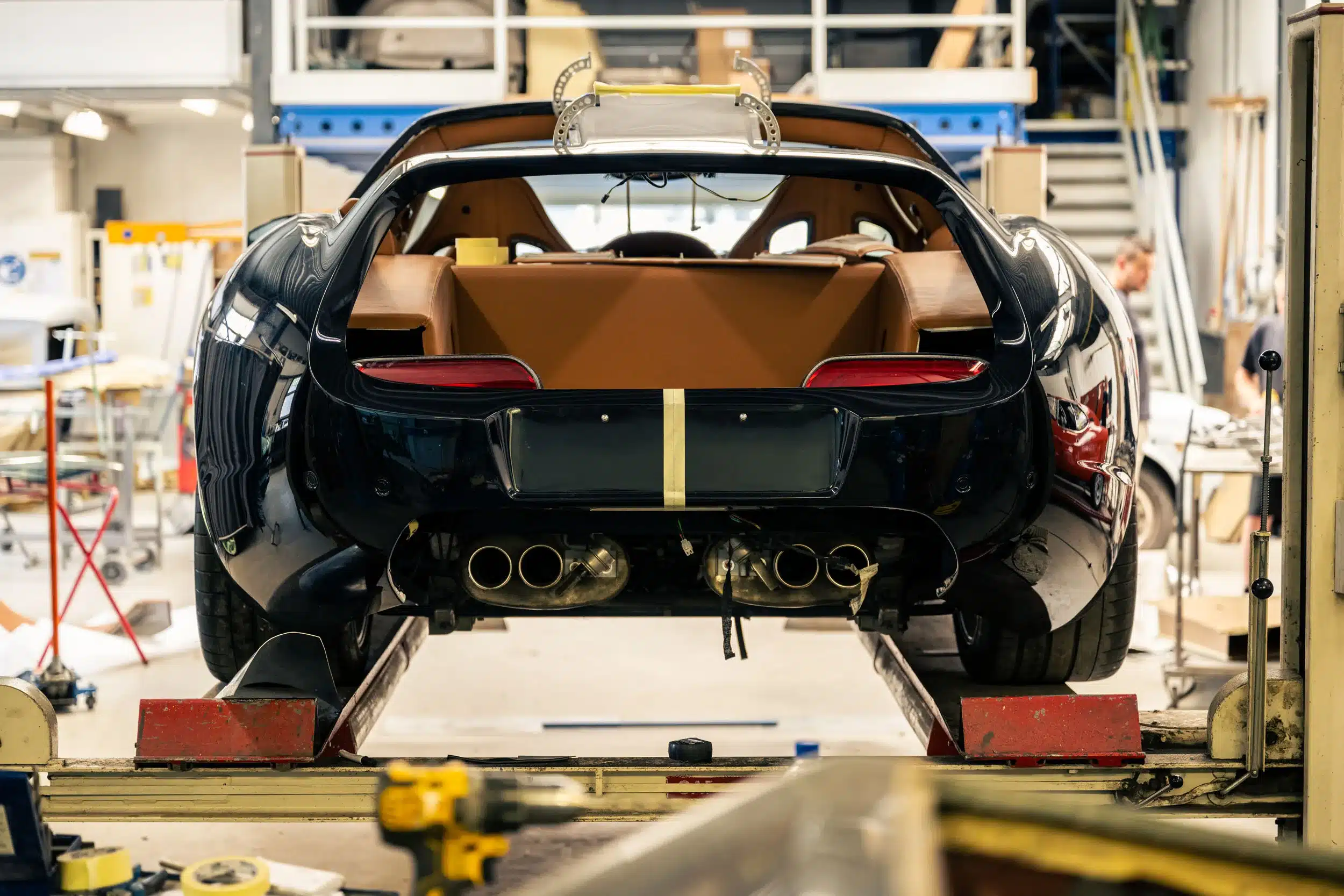 Daytona Shooting Brake Hommage im Werkstattumfeld, Blick auf das Heck mit sichtbaren Auspuffanlagen und luxuriösem Innenraum.