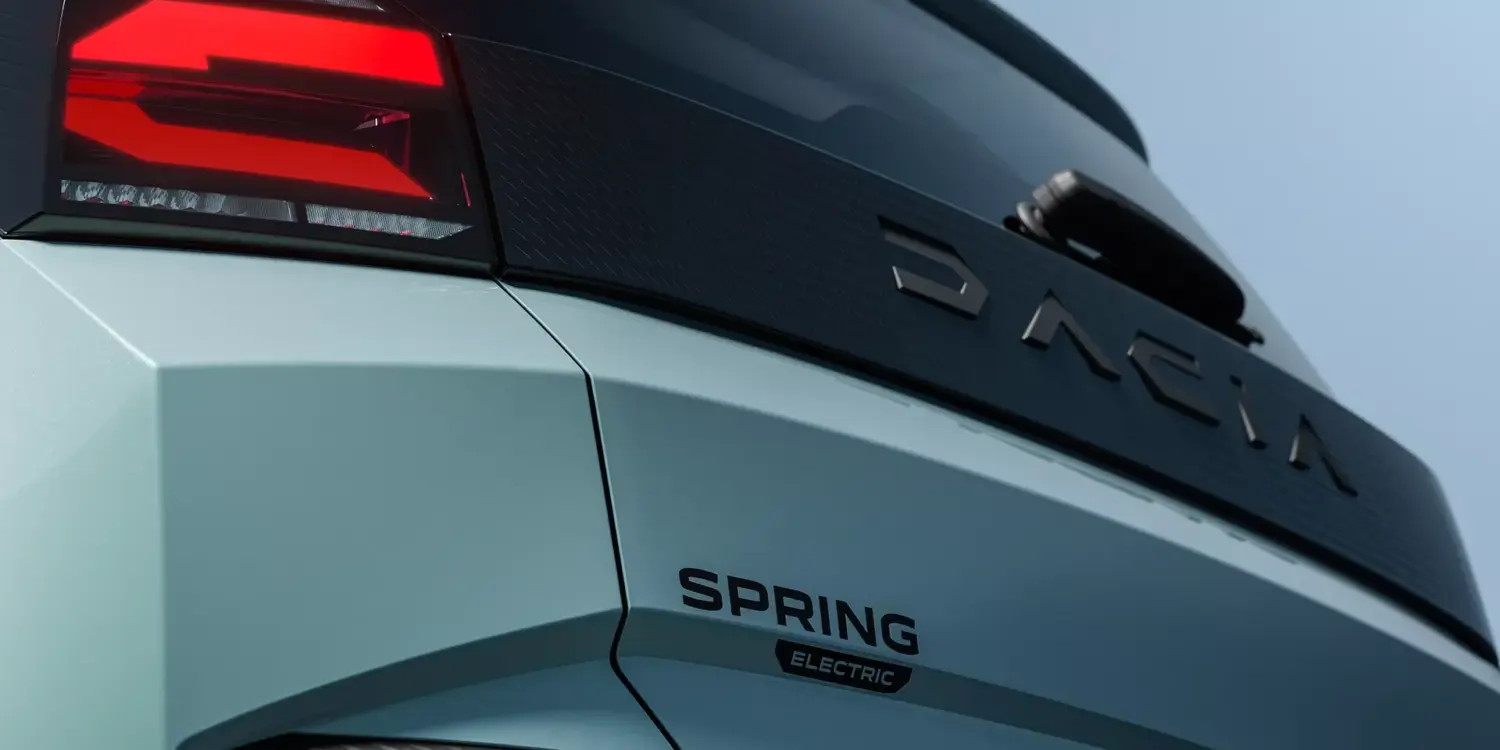 Nahaufnahme vom Heck des vollelektrischen Dacia Spring mit leuchtendem Rücklicht und Modellschriftzug