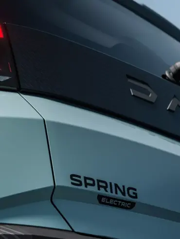 Nahaufnahme vom Heck des vollelektrischen Dacia Spring mit leuchtendem Rücklicht und Modellschriftzug