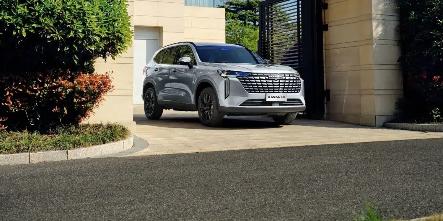 HAVAL H6 Hybrid SUV in Silber, frontal von schräg vorne, vor einem Haus geparkt