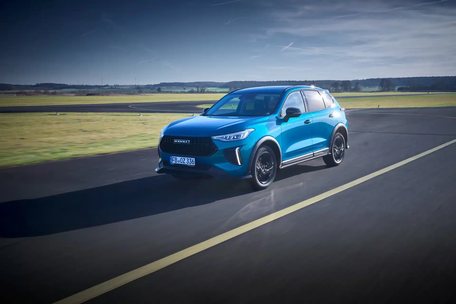 Blauer GWM HAVAL Jolion Pro fährt auf einer Landstraße bei Tageslicht.