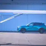 Seitliche Ansicht des GWM HAVAL Jolion Pro in Blau, geparkt auf einem Flugplatz mit Flugzeug im Vordergrund.