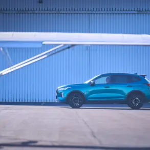 Seitliche Ansicht des GWM HAVAL Jolion Pro in Blau, geparkt auf einem Flugplatz mit Flugzeug im Vordergrund.