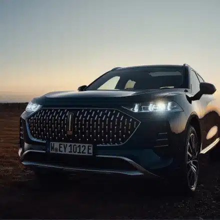 Frontansicht des WEY 05 Plug-in-Hybrid SUV bei Sonnenuntergang mit eingeschaltetem LED-Scheinwerfer.