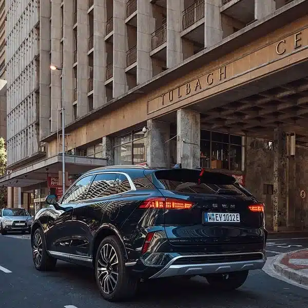 Rückansicht eines dunkelblauen GWM WEY 05 Plug-in-Hybrid-SUVs auf einer Stadtstraße vor einem Hochhaus
