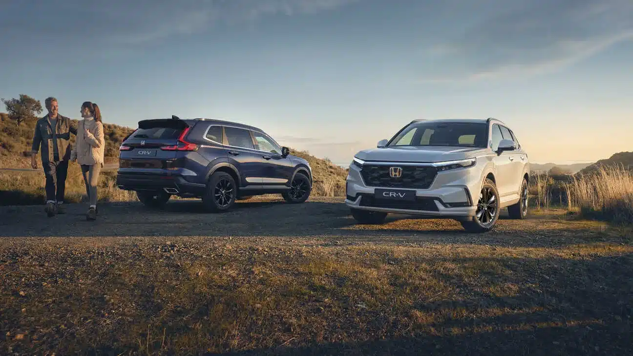 Zwei Honda CR-V der aktuellen Generation, einer von vorne und einer von hinten, auf einem Feldweg bei Sonnenuntergang.