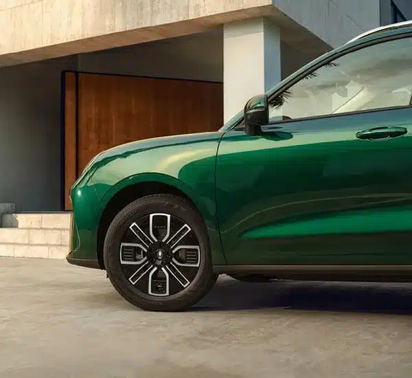 Seitenansicht des grünen GWM ORA 5 SUV vor modernem Gebäude mit Fokus auf Rad und Tür.