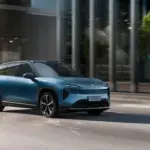 Blauer NIO EL7 (ES7) fährt auf einer städtischen Straße entlang moderner Gebäudefronten
