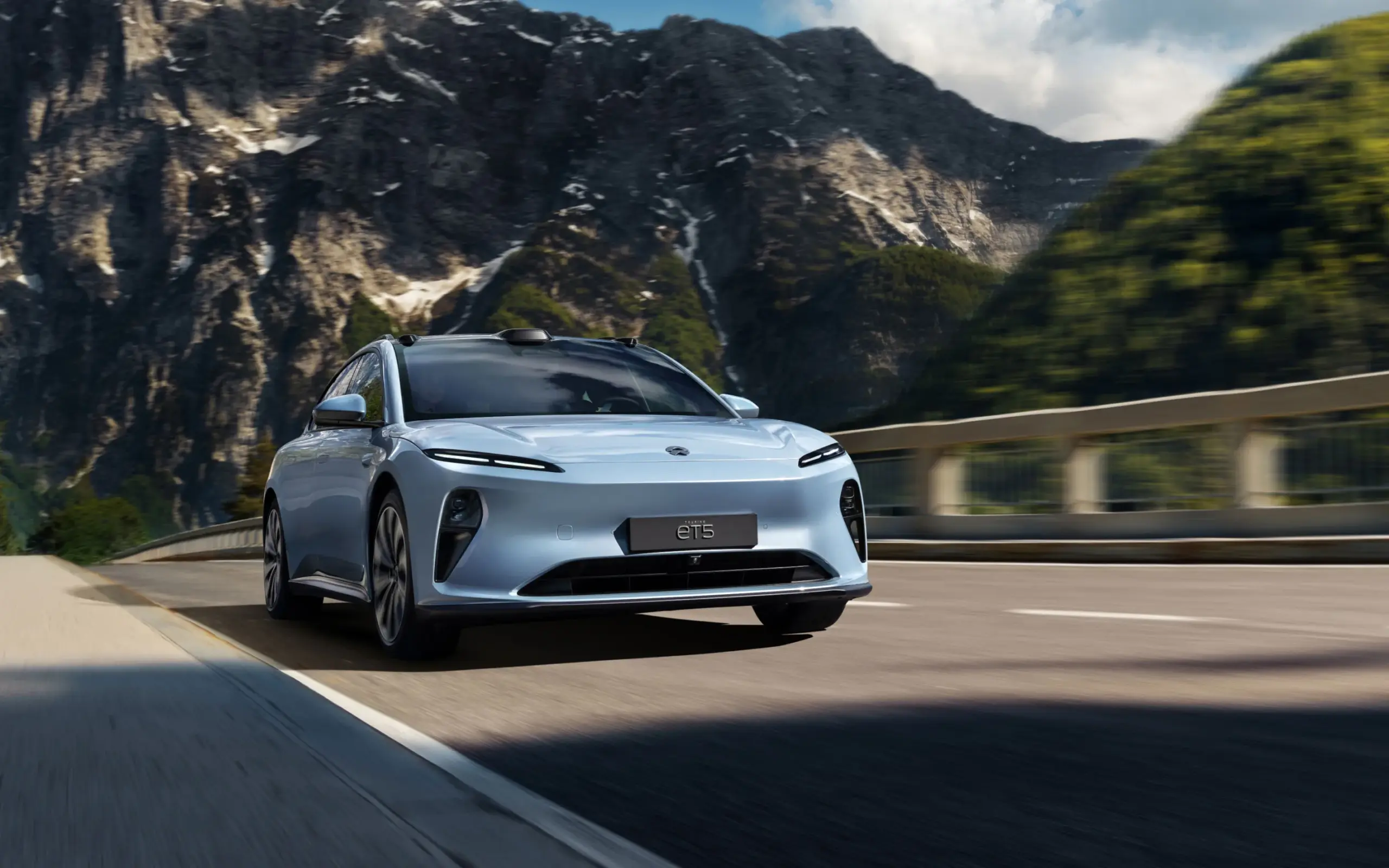 NIO ET5 Touring fährt auf einer Straße vor einer beeindruckenden Berglandschaft.