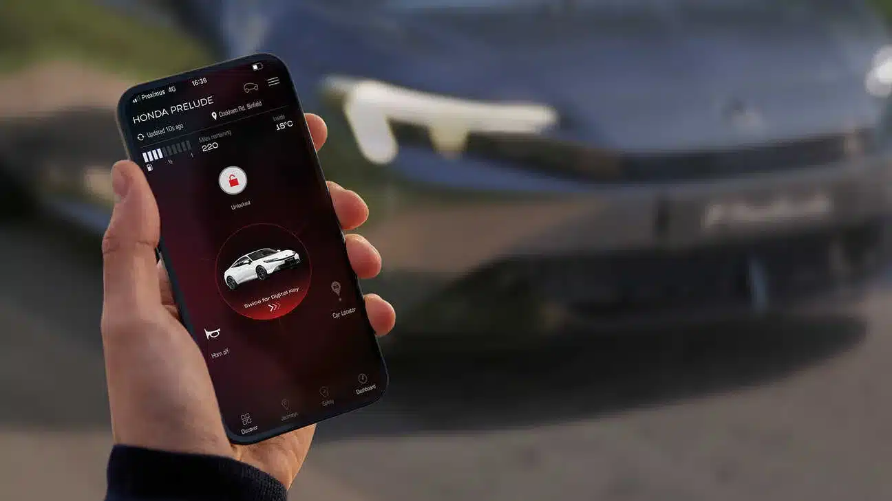 Hand hält ein Smartphone mit geöffneter My Honda+ App, die den Honda Prelude anzeigt, im Hintergrund das Fahrzeug.