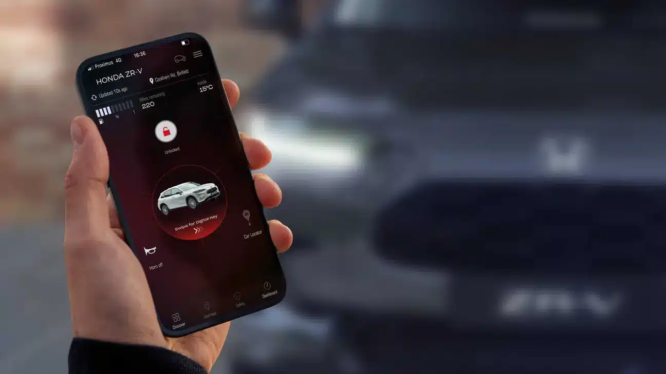 Hand hält Smartphone mit geöffneter My Honda+ App zur Fahrzeugsteuerung des Honda ZR-V vor der Front eines Honda ZR-V.