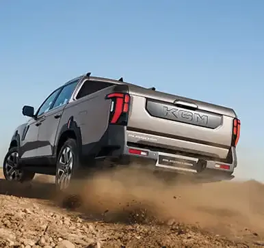 KGM Musso Grand Pick-up fährt auf einem staubigen Offroad-Weg