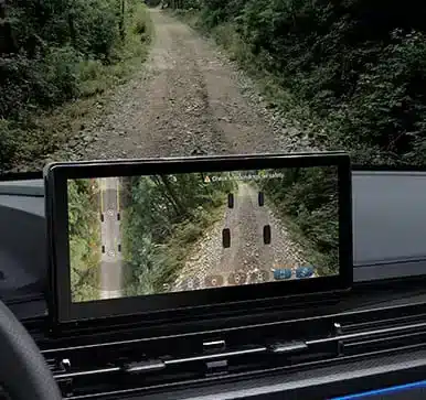 Display des KGM Musso Grand mit aktiver Unterbodenkamera auf Waldweg