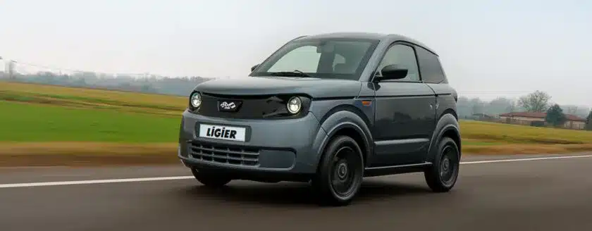 Ligier Myli MAX in Grau fährt auf einer Landstraße mit Feldern im Hintergrund