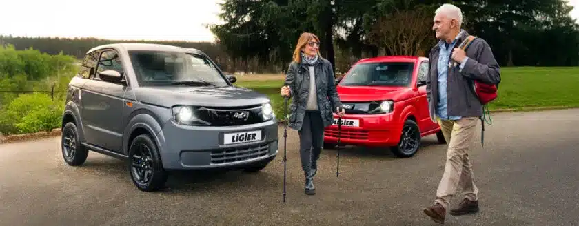 Ligier Myli MAX in Grau und Rot parkend auf offener Straße, mit zwei Personen davor