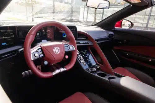 Innenraum des MG Cyberster mit digitalem Cockpit, Multifunktionslenkrad und roten Akzenten