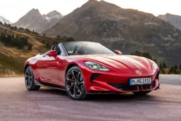 Roter MG Cyberster Roadster steht vor Berglandschaft mit offenem Verdeck.