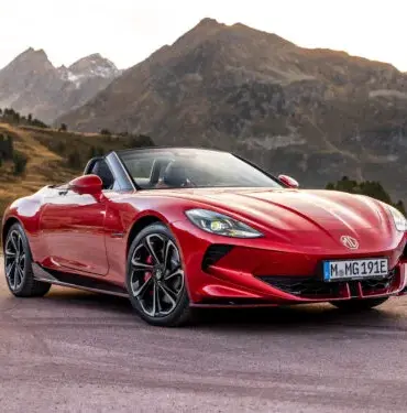 Roter MG Cyberster Roadster steht vor Berglandschaft mit offenem Verdeck.