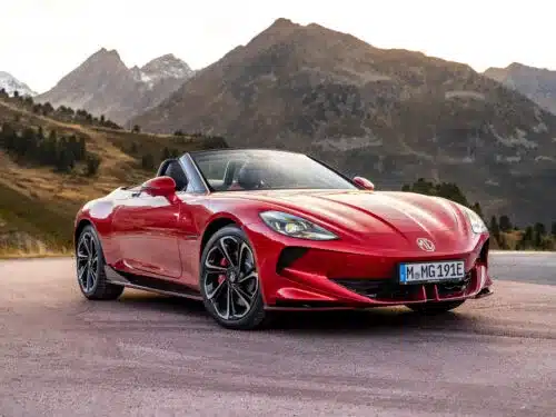 Roter MG Cyberster Roadster steht vor Berglandschaft mit offenem Verdeck.
