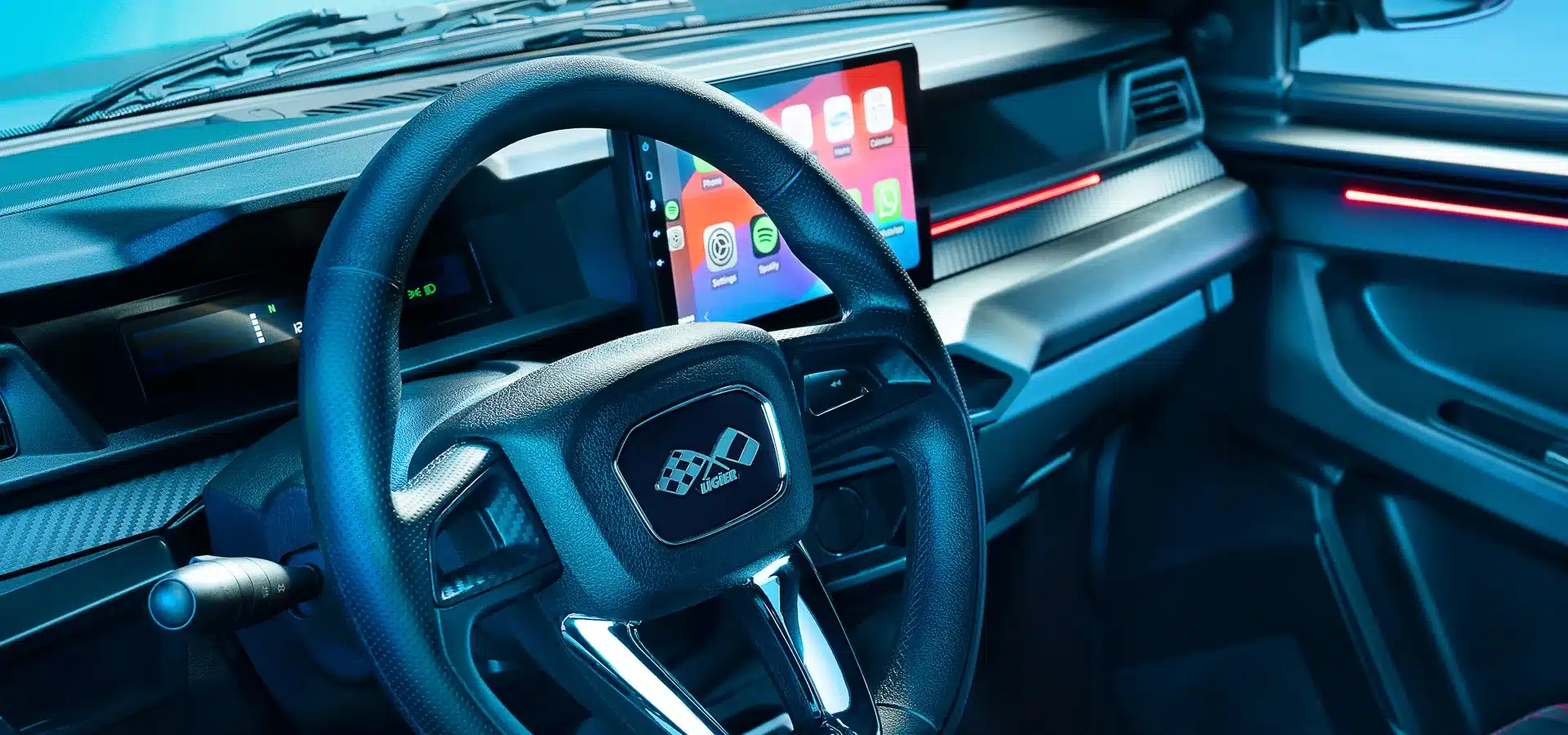 Innenraumansicht des Ligier JS50 mit Lenkrad, Touchscreen und Armaturenbrett in Carbon-Optik.