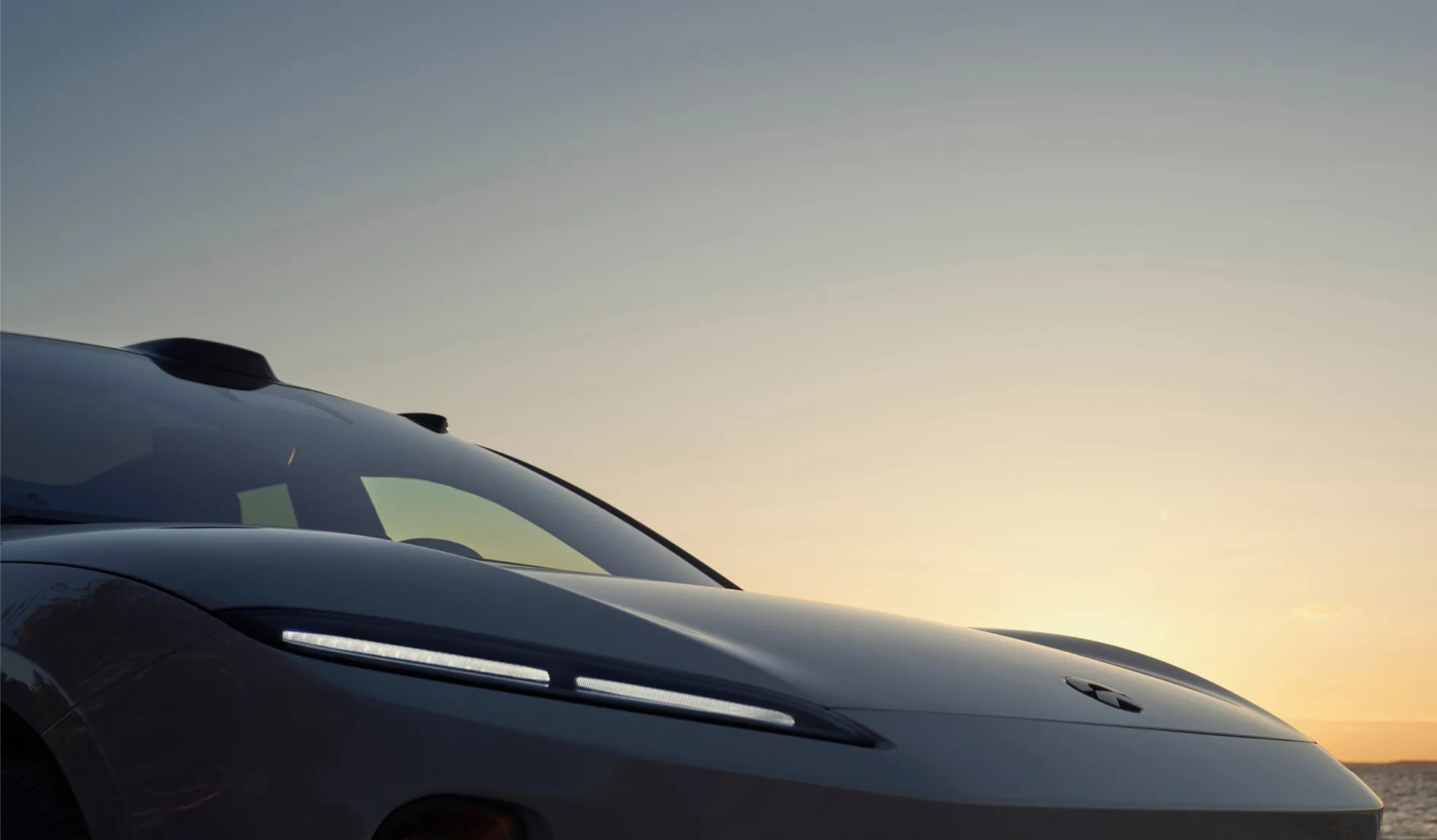Detailansicht der Fahrzeugfront eines modernen Elektroautos mit LED-Tagfahrlicht bei Sonnenuntergang