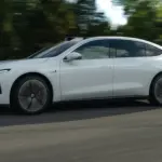 Weiße NIO ET7 Limousine fährt auf einer Straße, Seitenansicht, mit unscharfem Hintergrund.