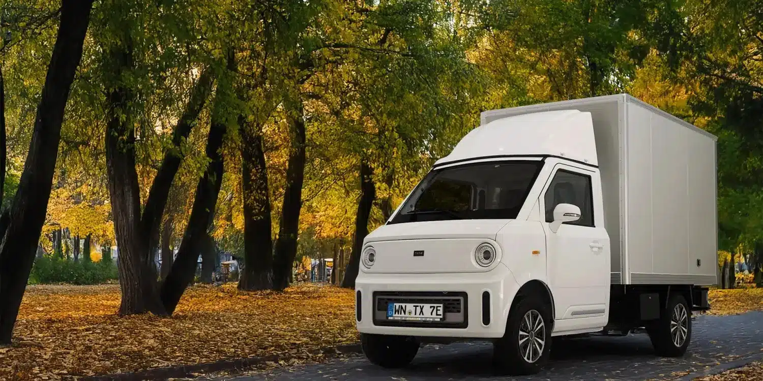 Weißer TYN-e TX7 Elektro-Transporter steht auf einer von Bäumen gesäumten Allee im Herbst.