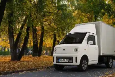 Weißer TYN-e TX7 Elektro-Transporter steht auf einer von Bäumen gesäumten Allee im Herbst.