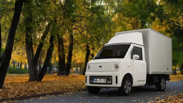 Weißer TYN-e TX7 Elektro-Transporter steht auf einer von Bäumen gesäumten Allee im Herbst.